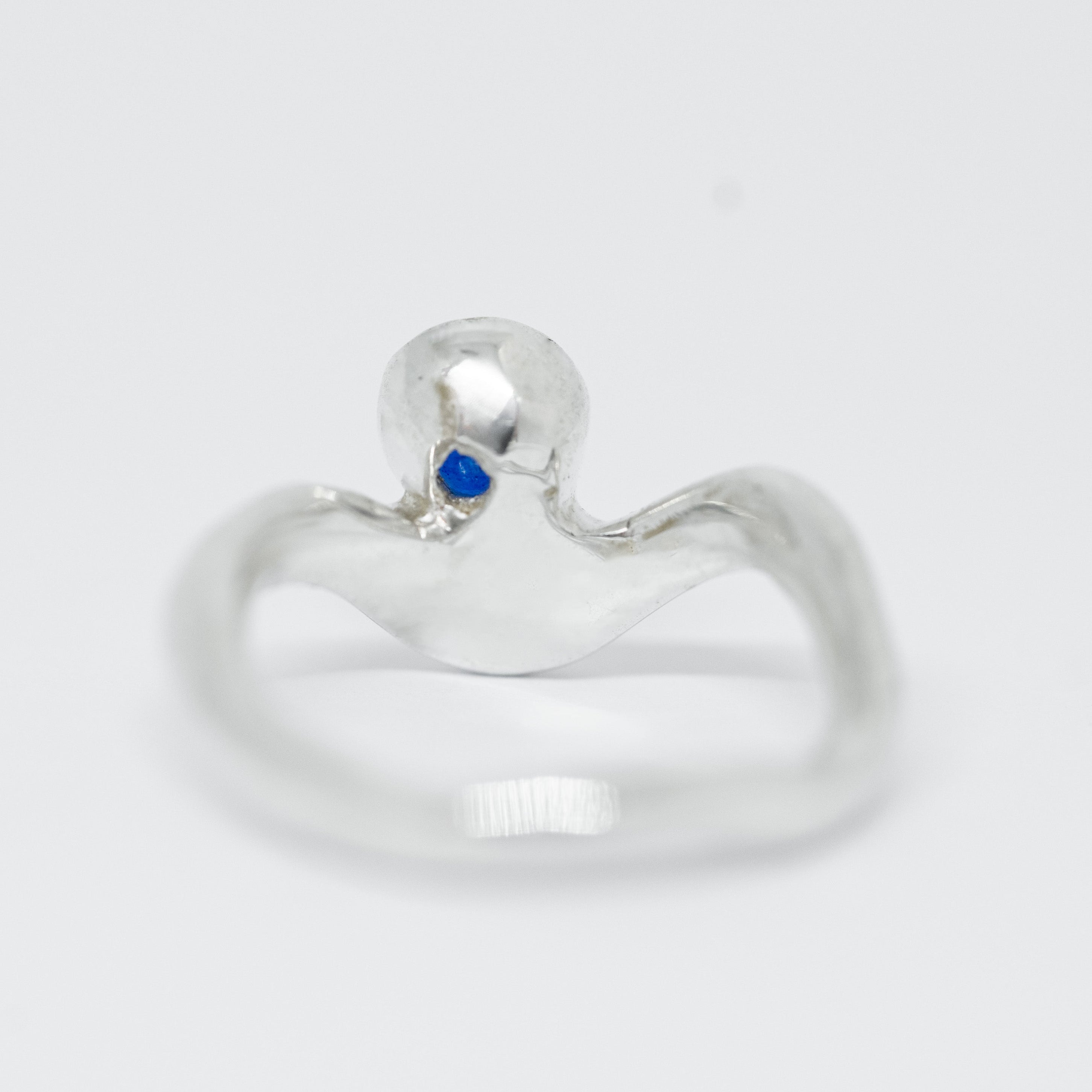 Silver ring with a blue gemstone on a white background