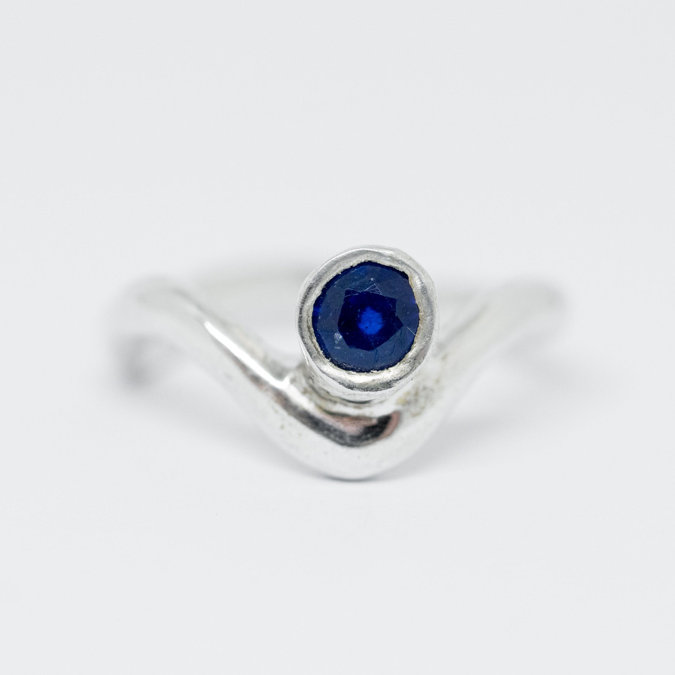 Silver ring with a blue gemstone on a light gray background