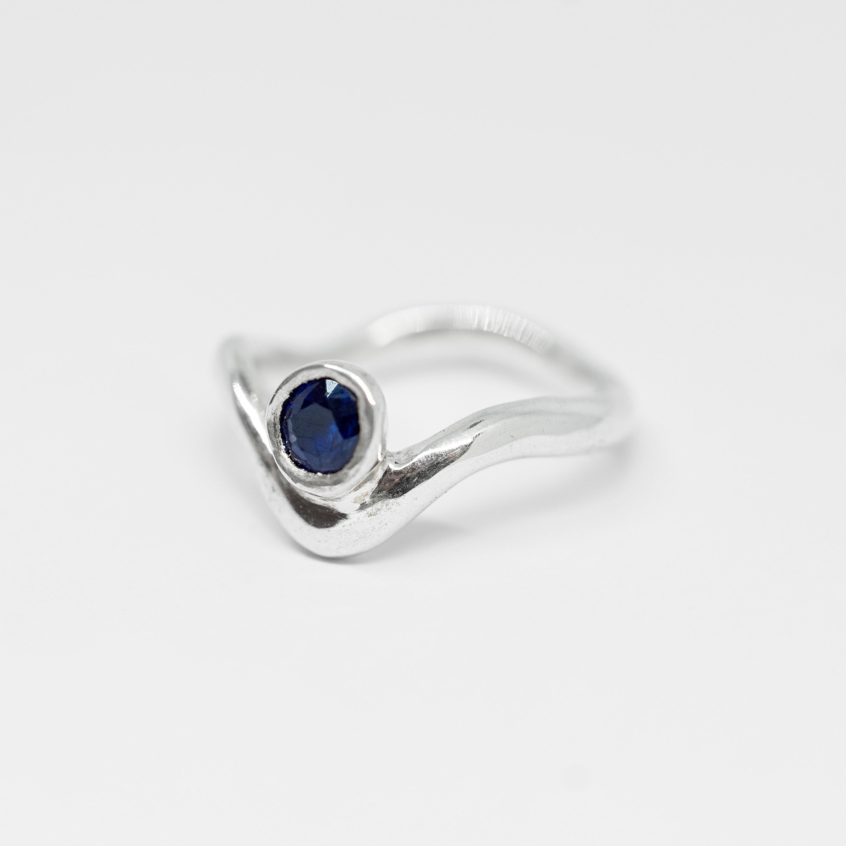 Silver ring with a blue gemstone on a light gray background