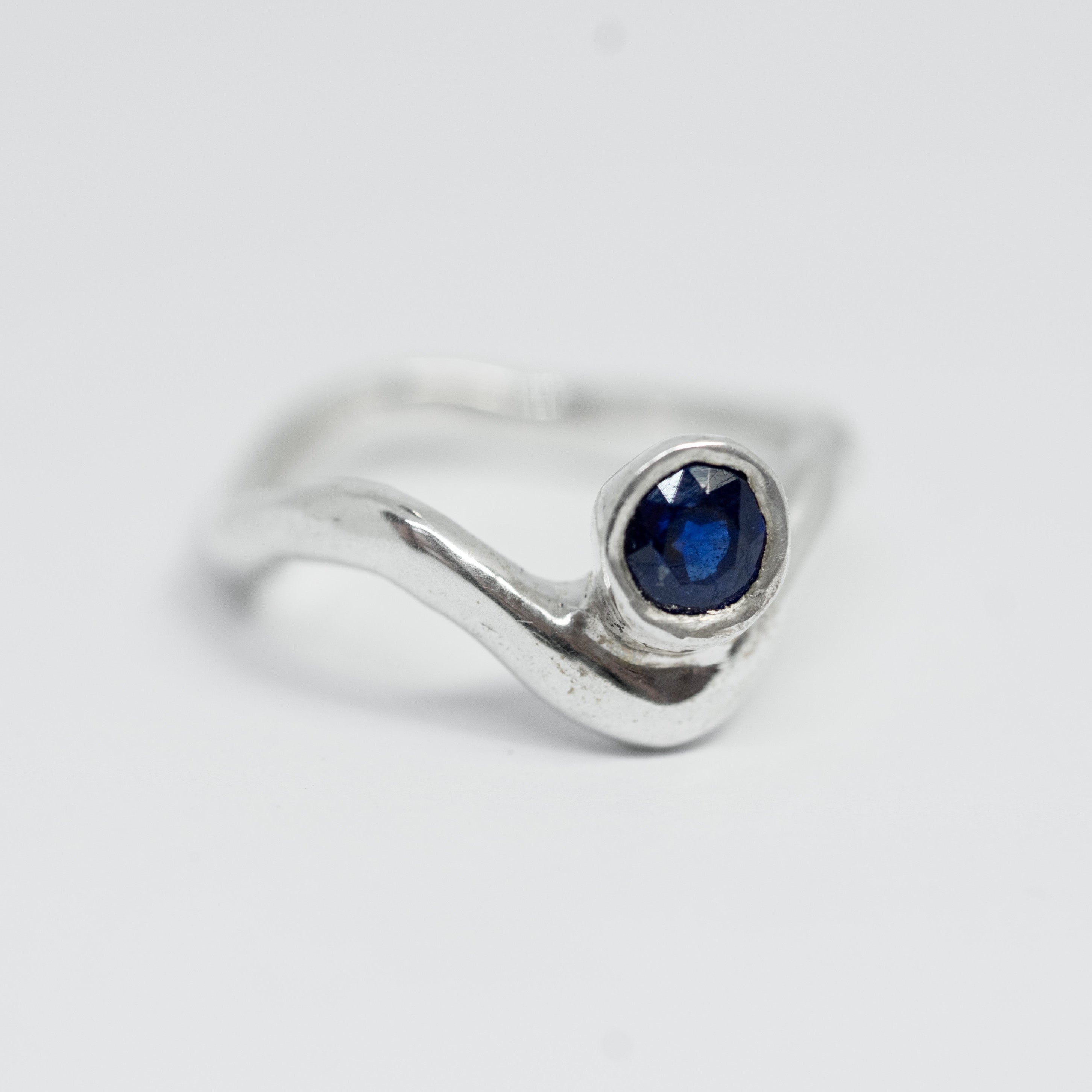 Silver ring with a blue gemstone on a light gray background