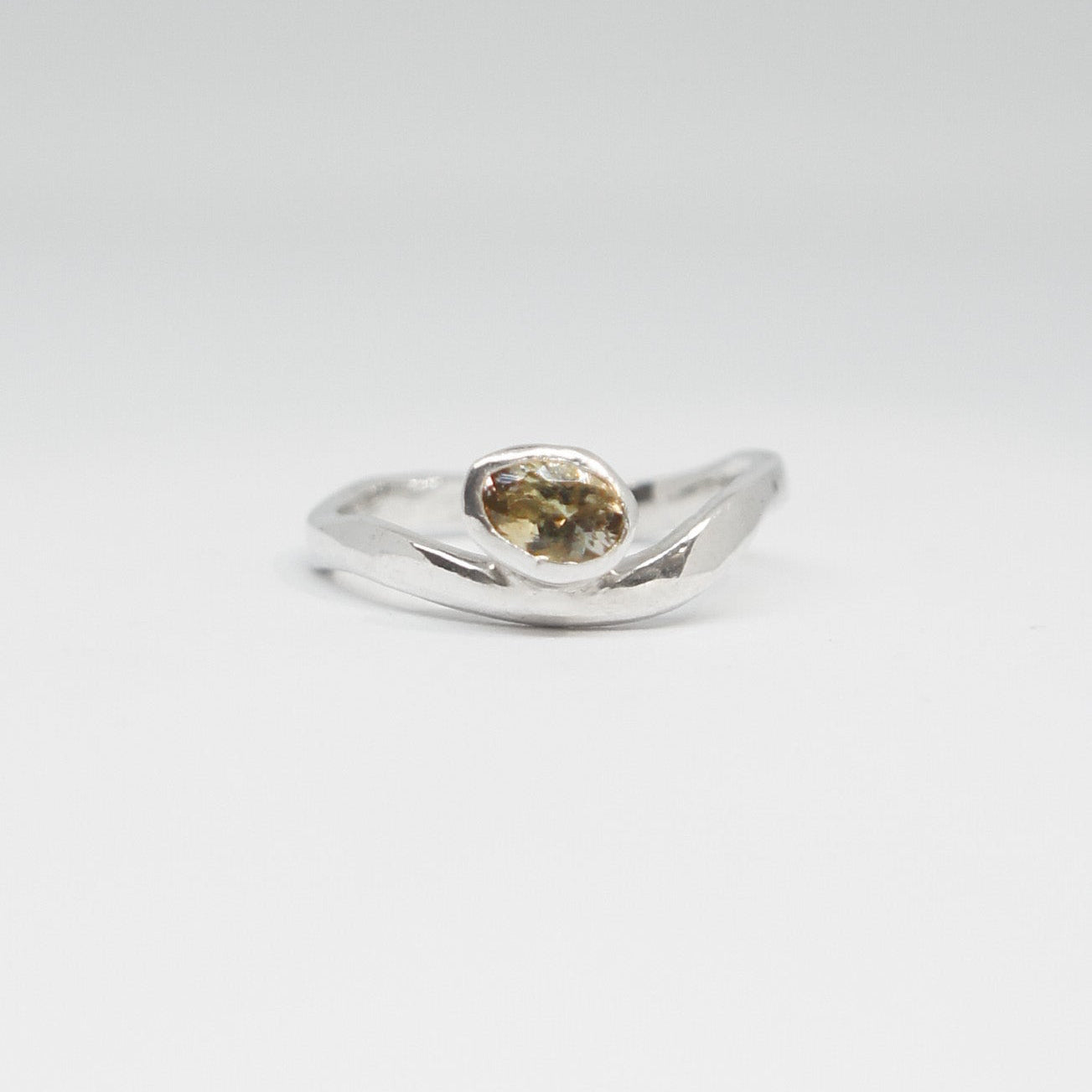 Silver ring with a green gemstone on a white background