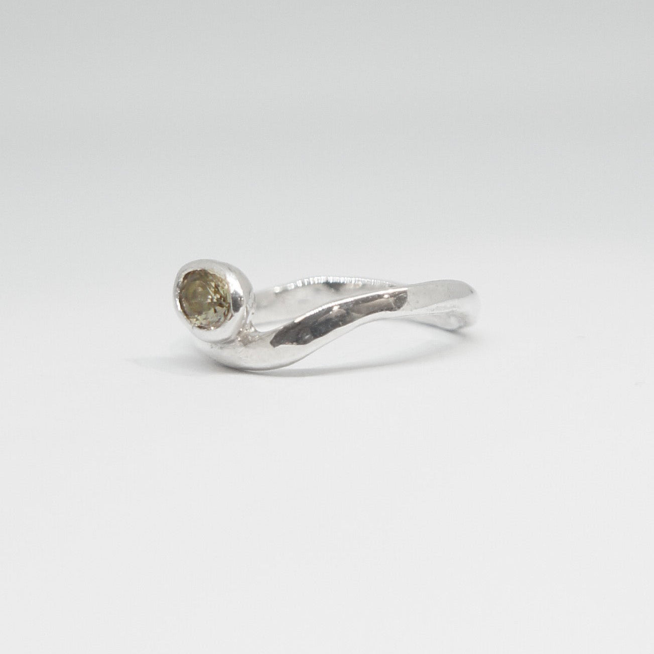 Silver ring with a small gemstone on a light gray background
