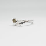 Silver ring with a small gemstone on a light gray background