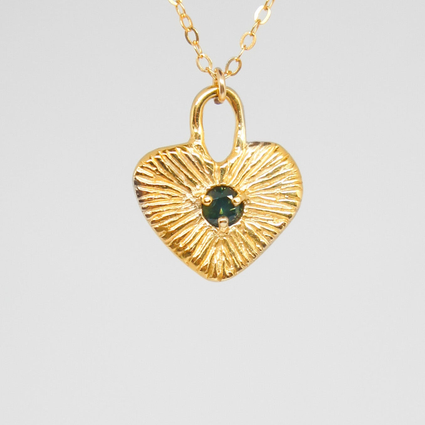 Gold heart-shaped pendant necklace on a gray background