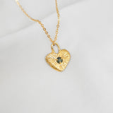Gold heart-shaped necklace with a pendant on a white background