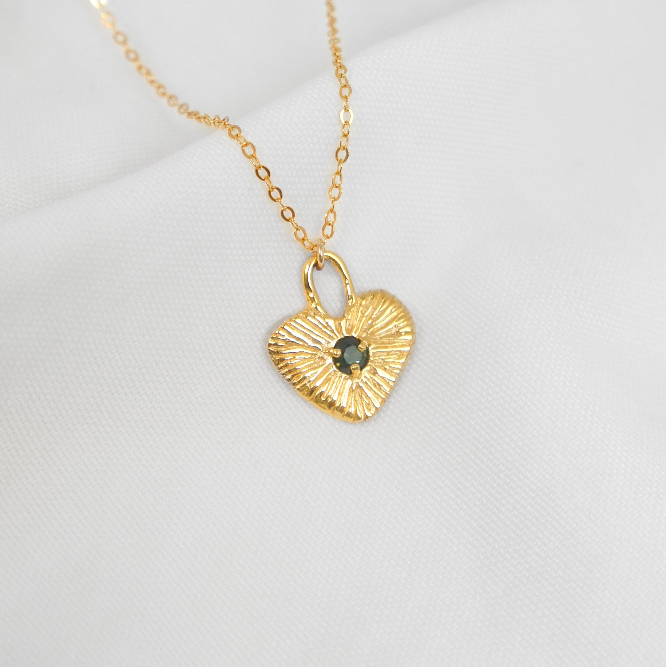 Gold heart-shaped necklace with a pendant on a white background