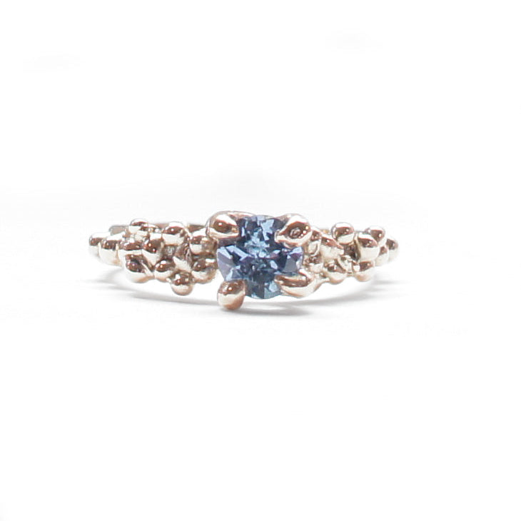 Yellow gold ring with a blue gemstone on a white background