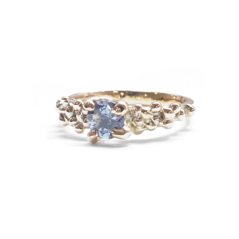 Gold ring with a blue gemstone on a white background