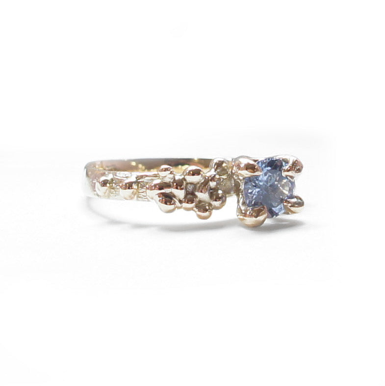Gold ring with a blue gemstone on a white background