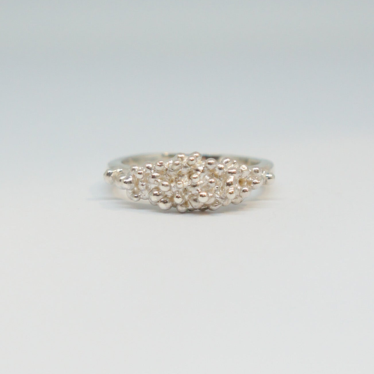 Silver ring with intricate design on a light gray background