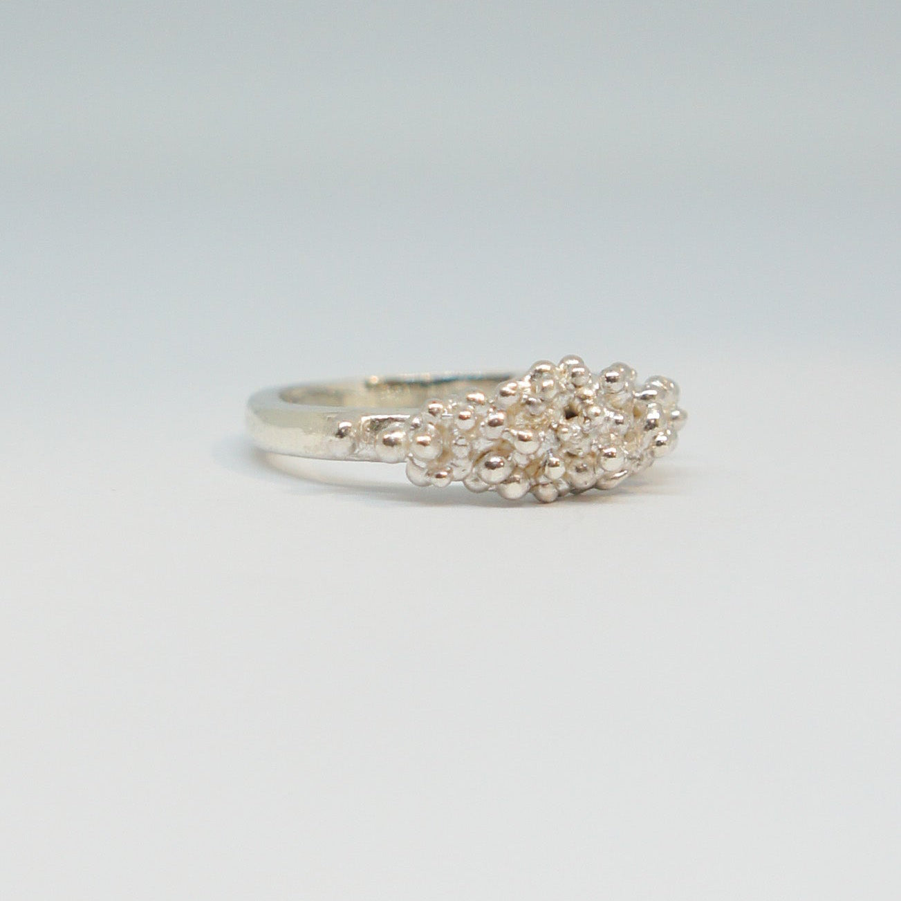 Silver ring with floral design on a light gray background