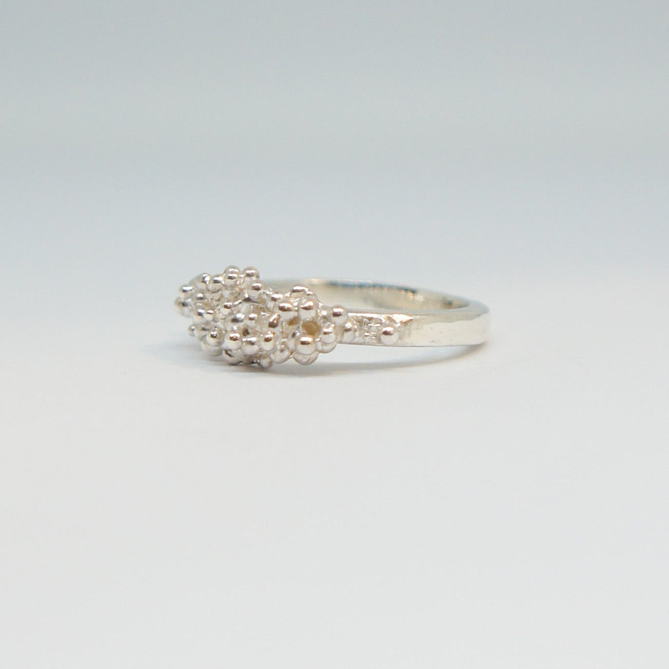 Silver ring with a textured design on a light gray background