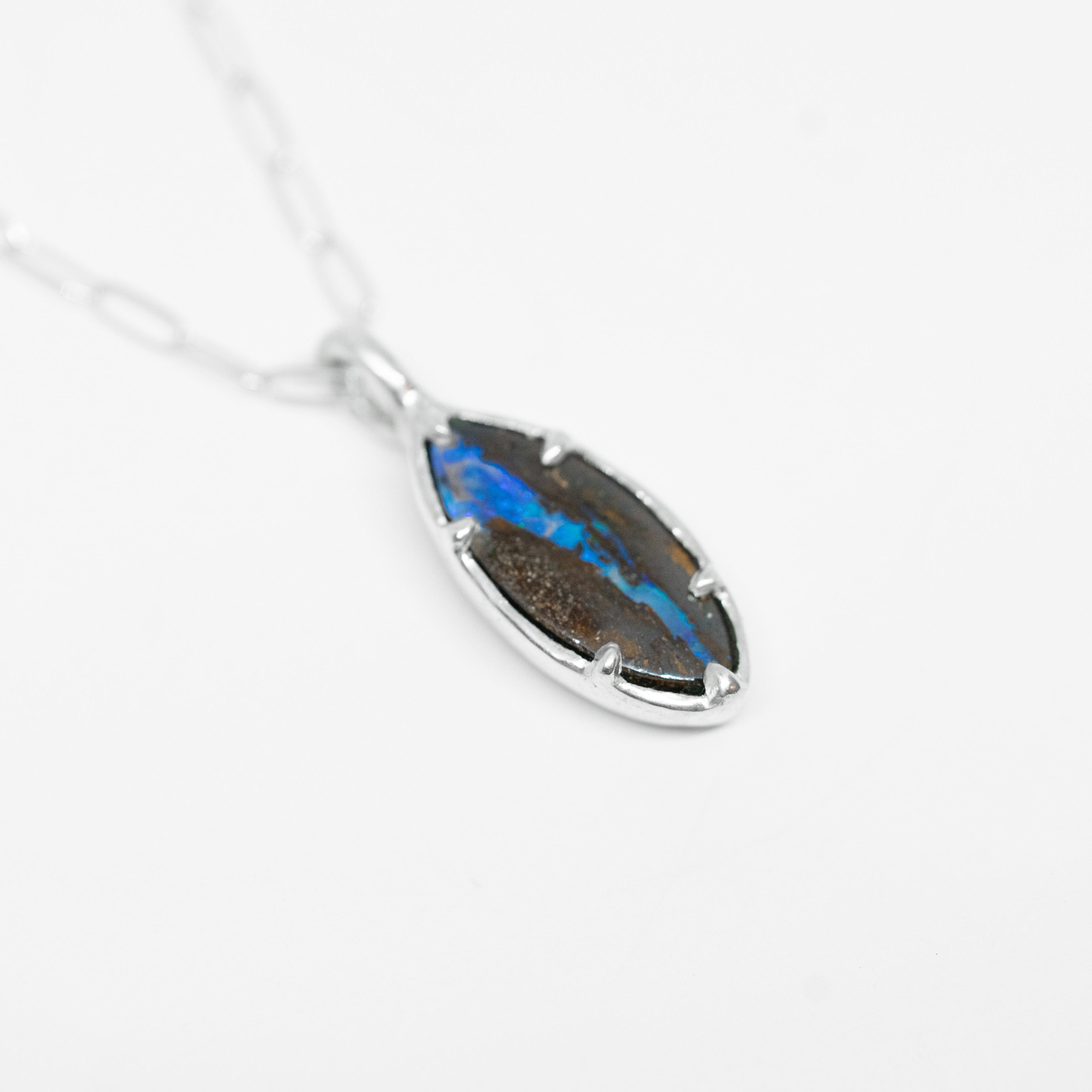 Silver necklace with a blue stone pendant on a white background