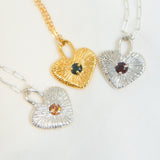 Three heart-shaped pendants on gold, silver, and gold chains against a white background.