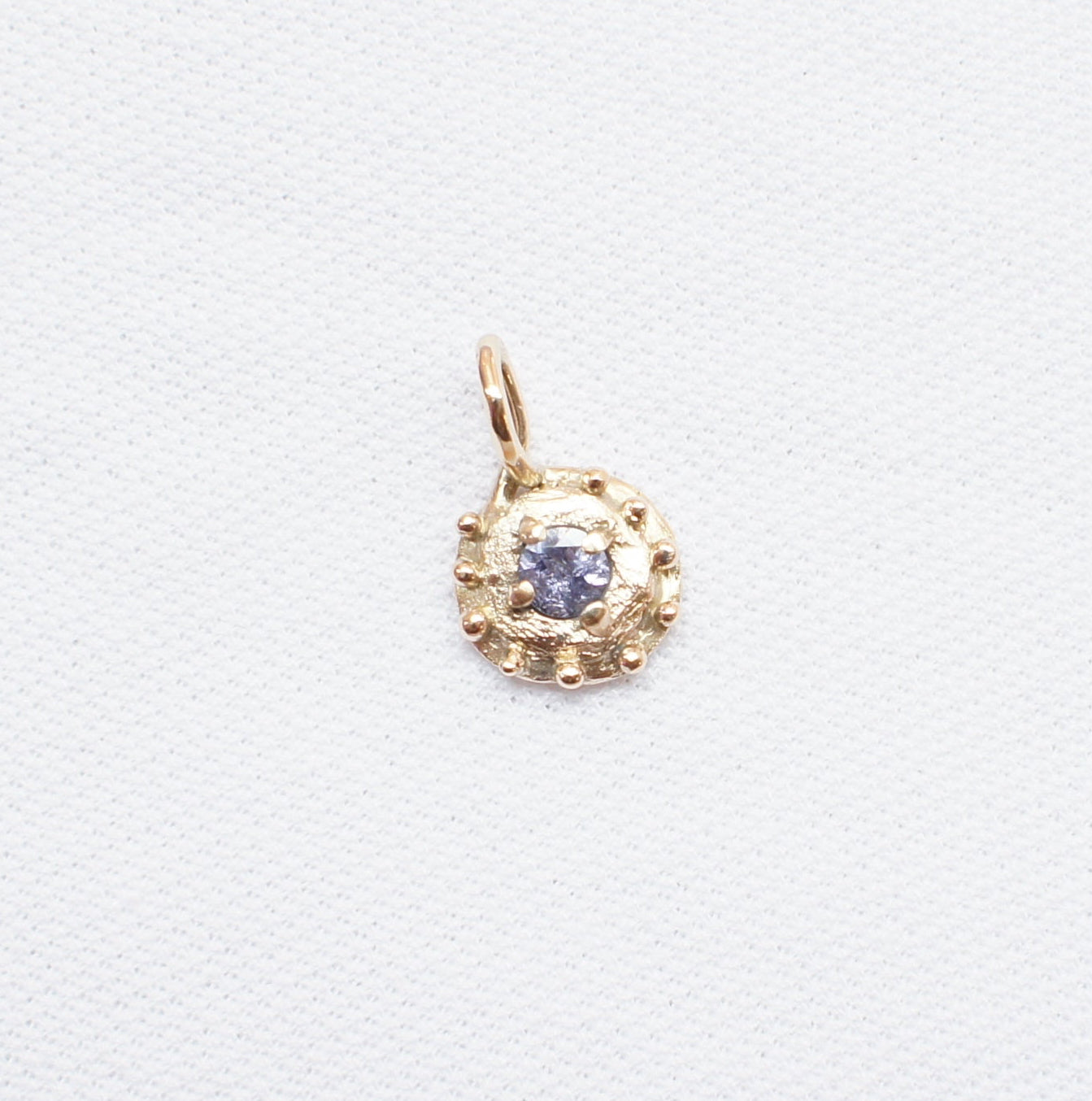 Gold pendant with a blue gemstone on a white background