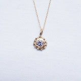 Gold necklace with a organic pendant on a light gray background