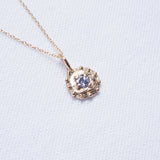 Gold necklace with a round pendant on a light blue background